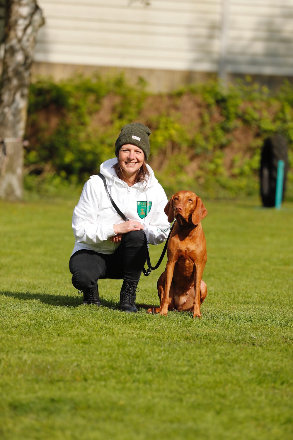 Doreen Donhauser sitzt entspannt mit ihrem Hund im Gras